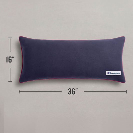 A Champion Faux Wool Body Pillow in a rectangular navy blue design with red piping, measuring 16 by 36 inches, rests on a gray surface. This cozy accent from Champion features a small branded logo tag on the corner, making it an ideal addition to any space.