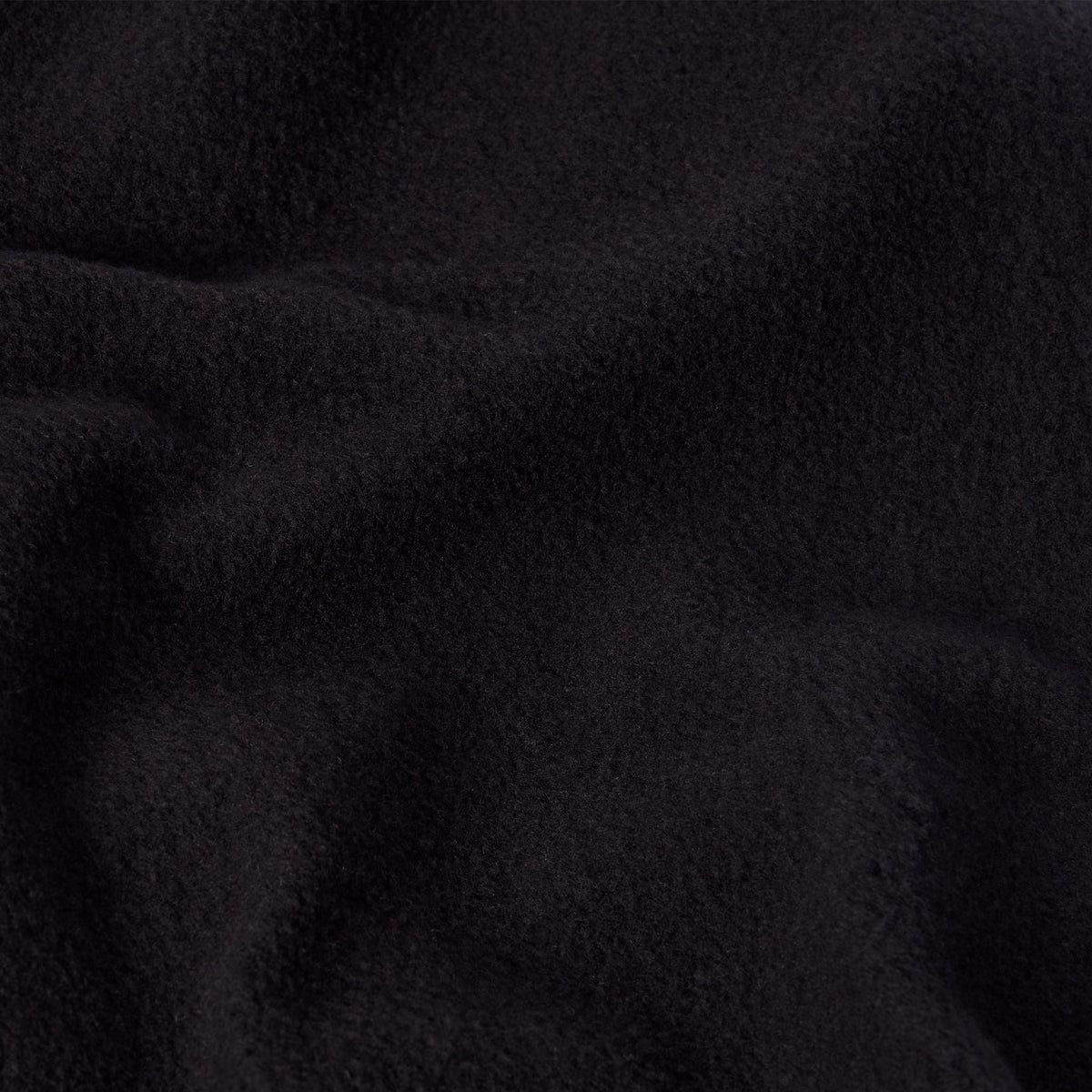 A close-up of soft, black fleece fabric, commonly found in Champion Women’s Knitted Flare Pants, highlighting its textured surface and gentle folds.