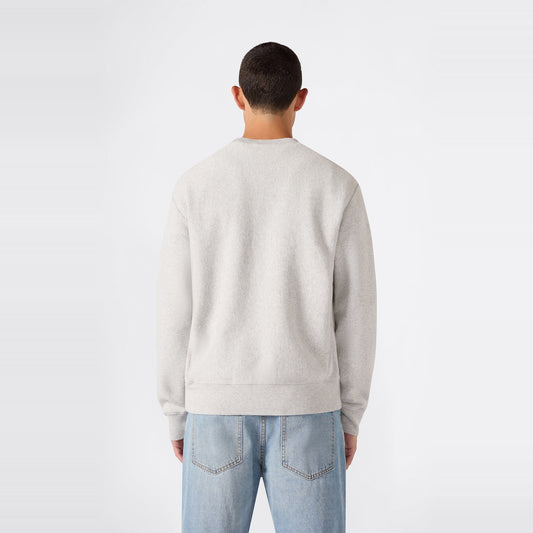 A person with short dark hair is pictured from behind, wearing a light gray Champion Men’s Relaxed Fit Crewneck Sweatshirt and light blue jeans against a plain white background.
