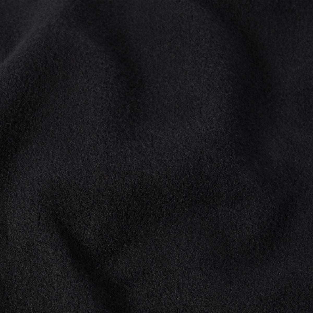 Close-up of soft, deep black fabric with a subtly fuzzy texture and gentle folds, evoking the feel of a classic Champion Men’s Knitted Crewneck Sweatshirt.