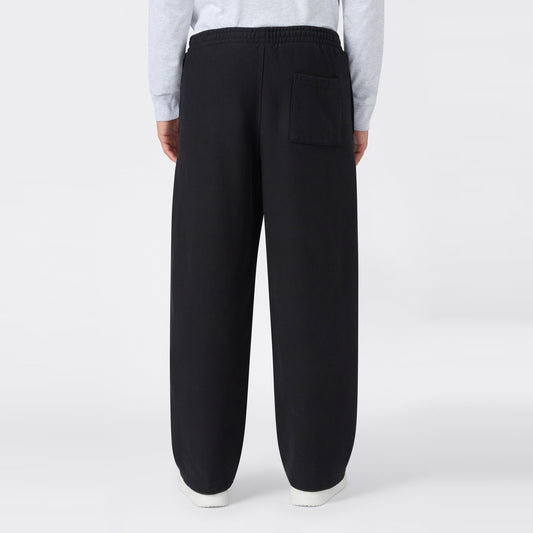 A man wearing Champion Men’s Knitted Wide Leg Pants, featuring a loose fit, elastic waistband, and a single back pocket, stands with his back to the camera against a plain white background.