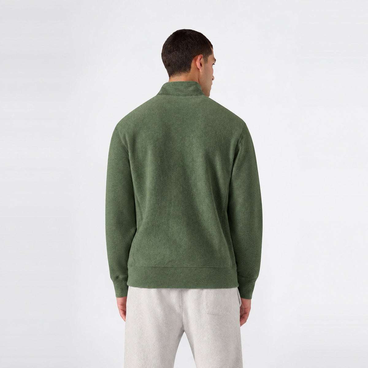 Back view of a person wearing a green Champion Men’s Knitted Half Zip Sweatshirt and grey sweatpants.