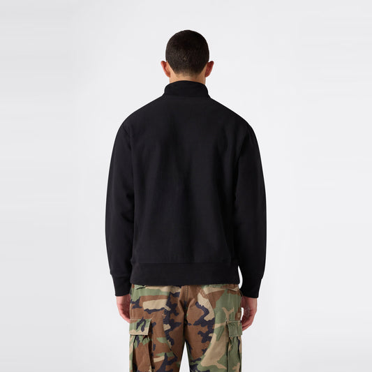 A person stands facing away, wearing a black Champion Men’s Knitted Half Zip Sweatshirt and camouflage cargo pants against a plain white background.