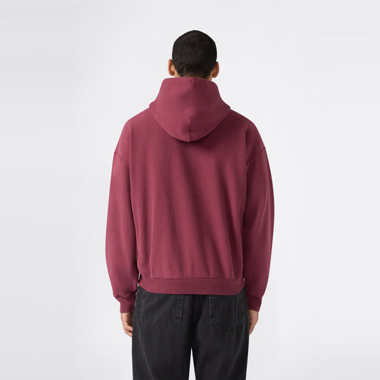 A person wearing a maroon Men’s Knitted Hooded Sweatshirt by Champion and black jeans stands facing away from the camera against a plain white background.