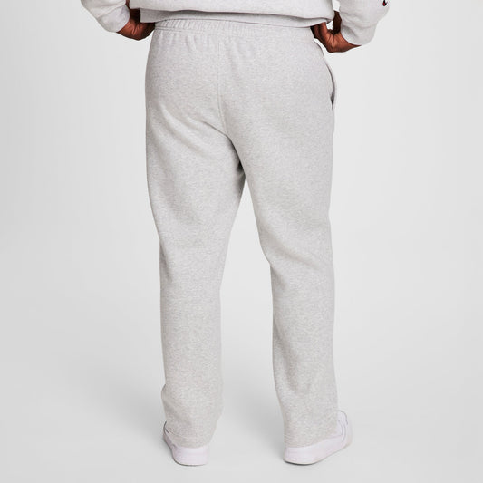 A person stands facing away against a white background, wearing Champion Powerblend Sweatpants, Open Hem, C Logo - Big & Tall in light gray with a matching sweatshirt and white sneakers. Hands are on hips.