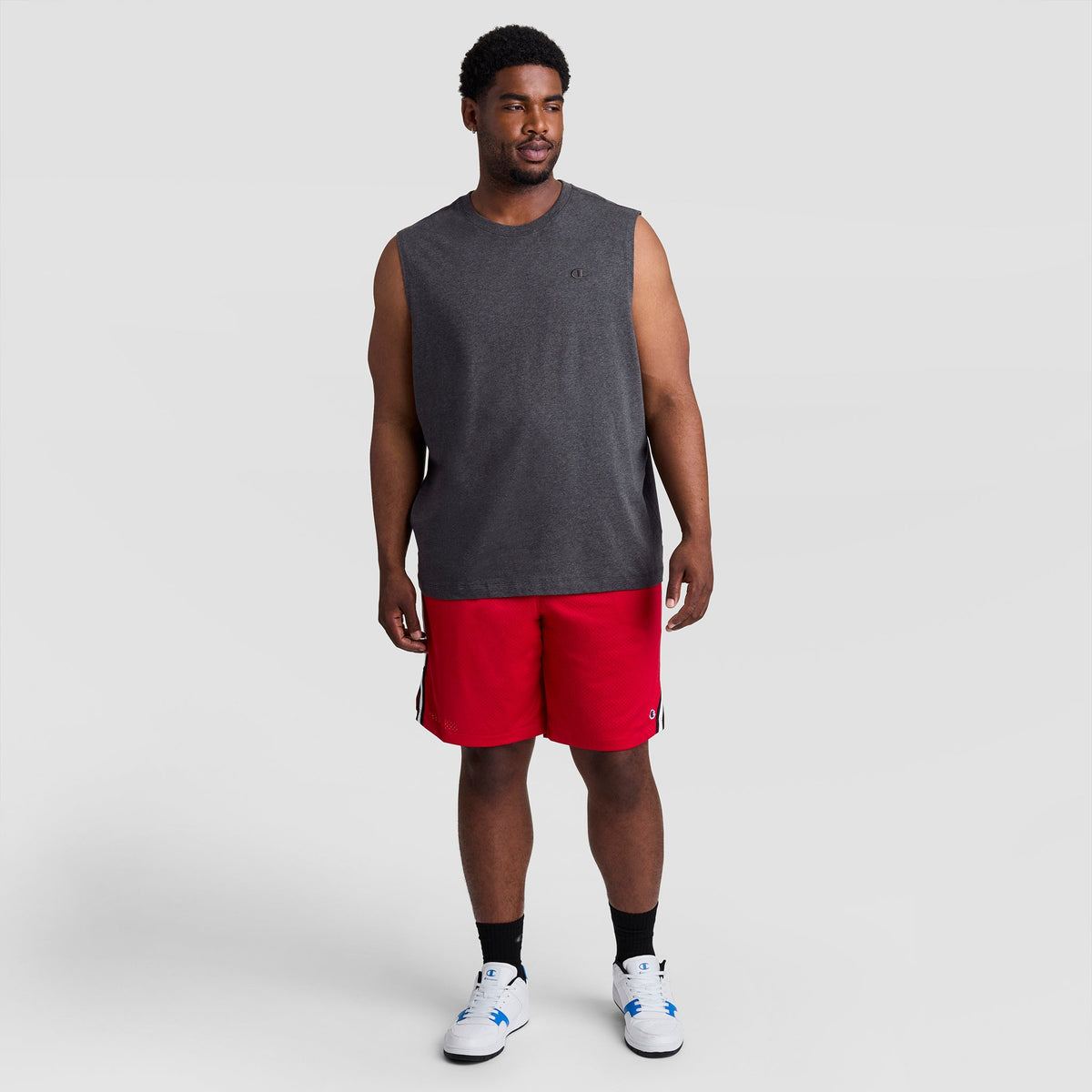 A man wearing a grey Muscle Tank, C Logo - Big & Tall and red athletic shorts.