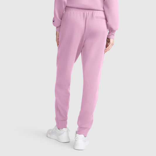 A person wearing Champion Taper Leg Jogger with Zippers in light pink, paired with a matching pink sweatshirt and white sneakers, stands with their back to the camera against a plain white background.