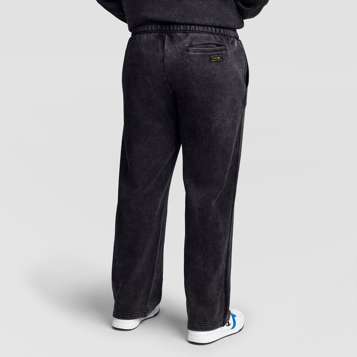 Rear view of dark grey Champion Mineral Wash Open Hem Pant with a vintage look, featuring an open hem and a back pocket with a small logo patch.
