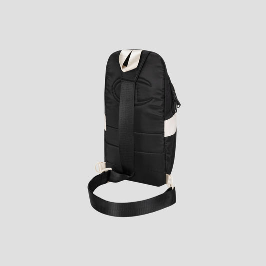 A black Champion Oracle Sling Pack crossbody bag with a wide adjustable shoulder strap and white accent detail, shown from the back against a plain light gray background.