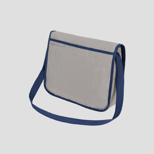 The Champion Phase Messenger Bag, featuring a light gray body with dark blue trim and a matching blue shoulder strap, is showcased against a plain light background. Designed with urban commuters in mind, this bag offers both style and functionality with its flap closure and padded laptop sleeve for added protection on the go.
