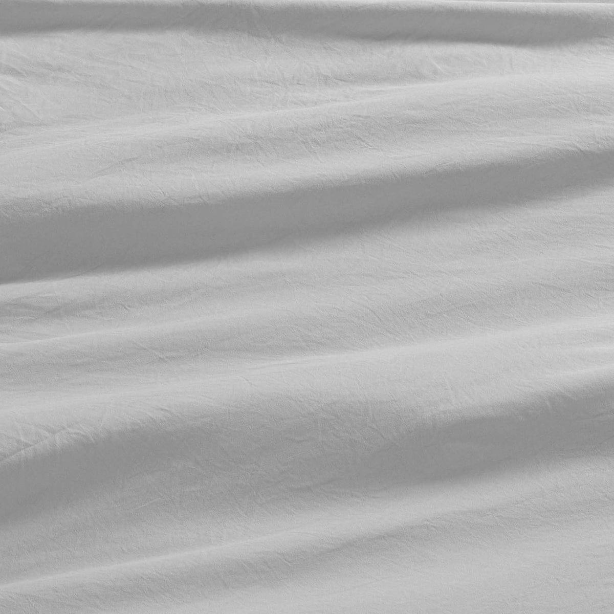 Close-up of white, slightly wrinkled fabric with soft shadows and gentle folds, creating a subtle textured pattern across the surface—evoking the smooth comfort of the Champion Elastic Logo Microfiber Sheet Set.