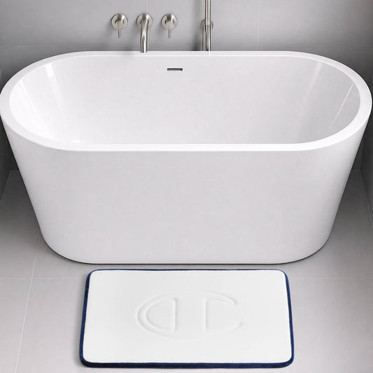 A modern white bathtub with a wall-mounted faucet, and a rectangular Champion Quilted Logo Memory Foam Bath Mat, offering cushioned comfort, placed on a gray tiled floor.