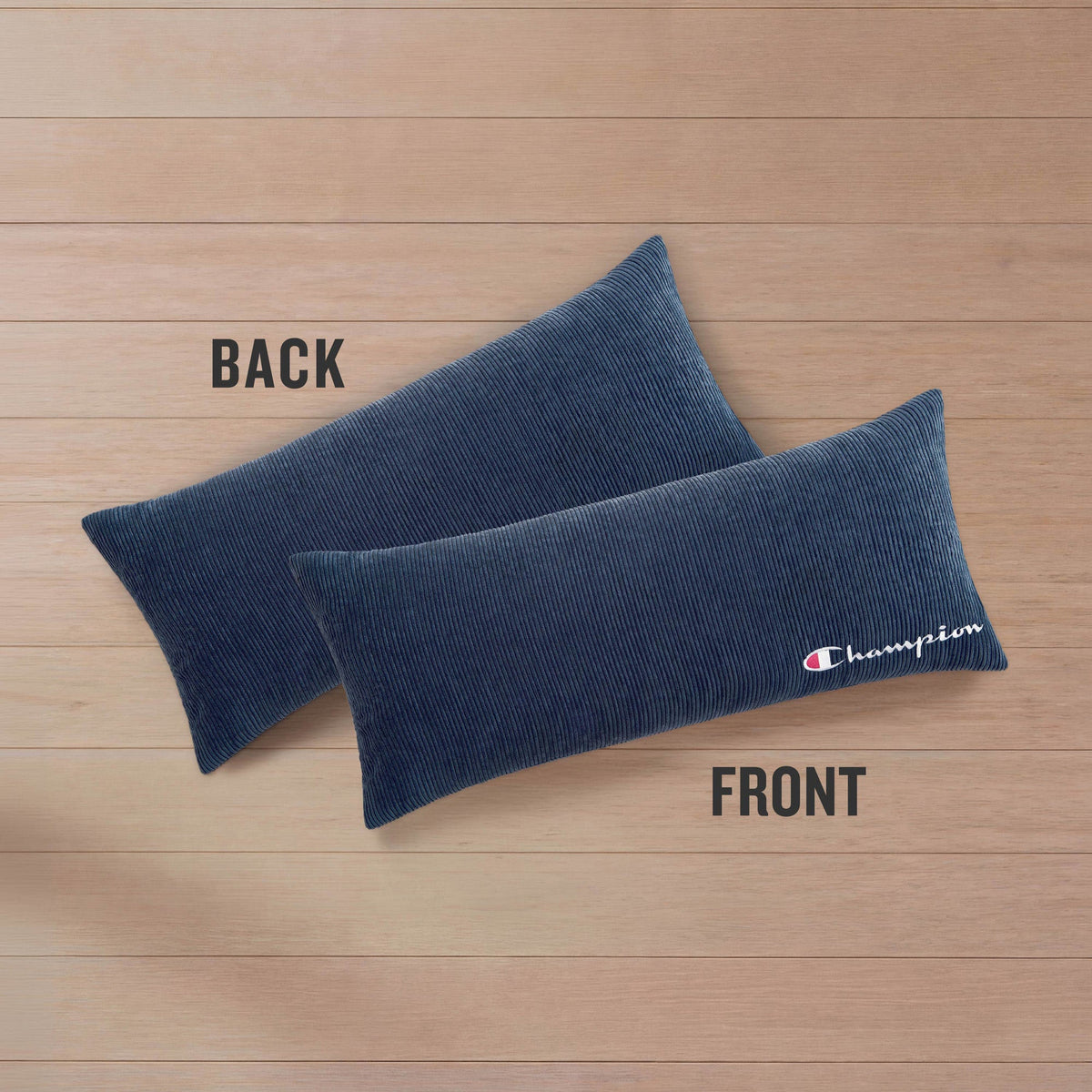 Two Champion Corduroy Body Pillows are displayed on a wooden surface. One pillow is labeled BACK, while the other, labeled FRONT, showcases an embroidered Champion logo in white and red. Designed by Champion, these pillows bring both signature style and comfort to any lounging area.