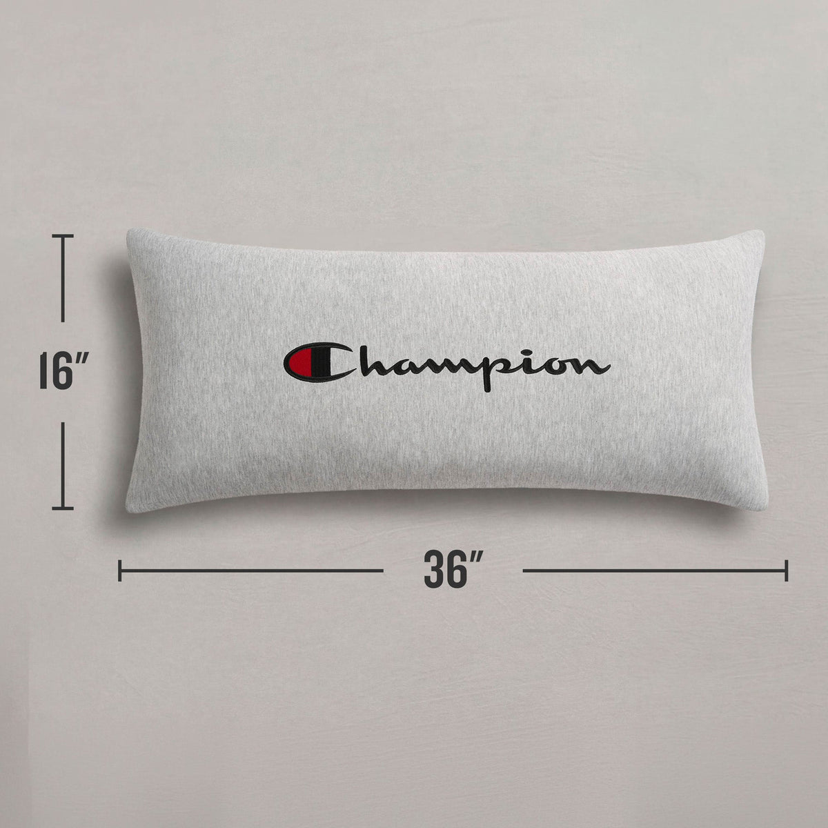 A Champion Jersey Body Pillow in gray, featuring the "Champion" logo in bold black and red font. Made from soft jersey-knit polyester, this rectangular pillow by Champion offers full-length cushioning and measures 16 inches tall by 36 inches wide, displayed against a light background.