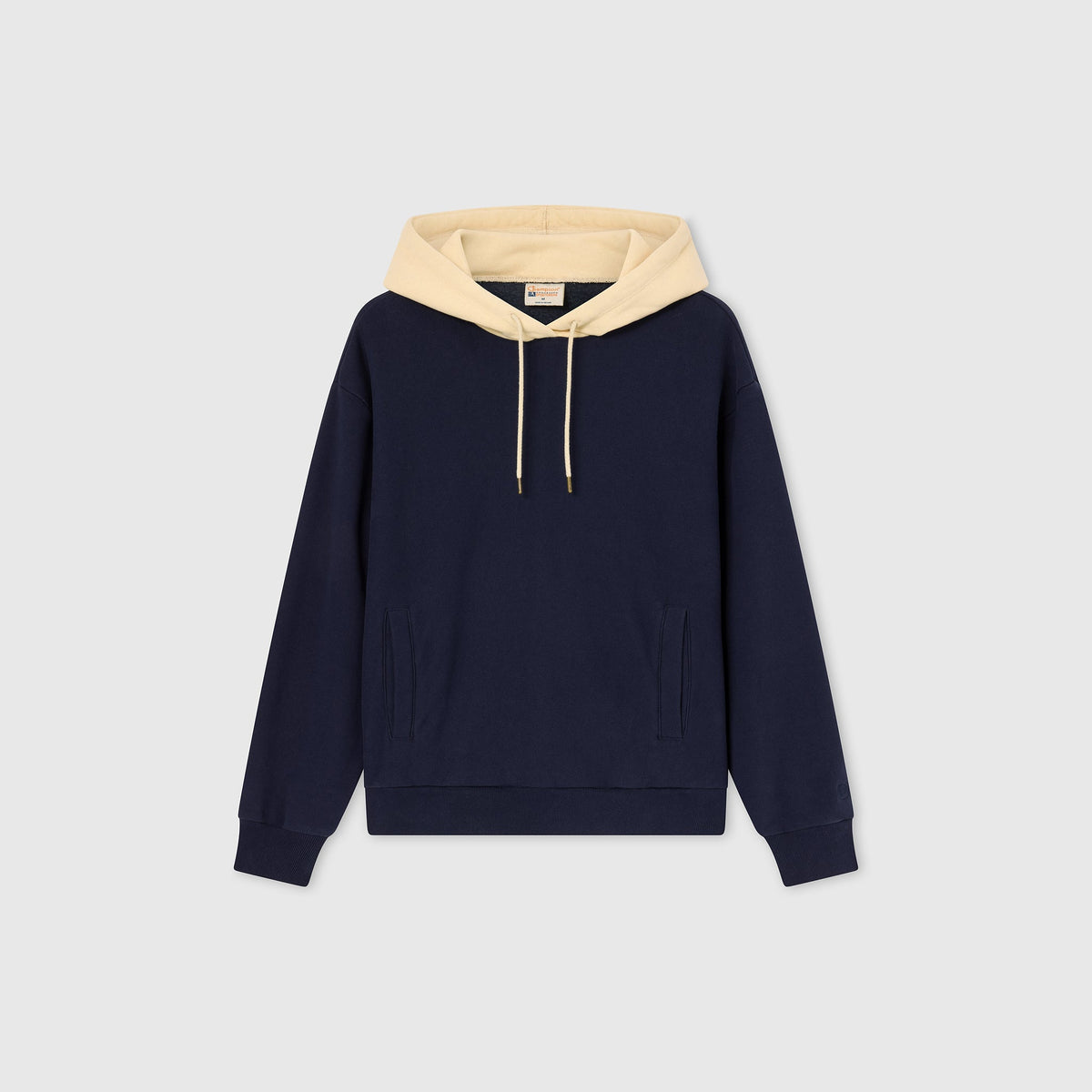 A Champion Women’s Knitted Hooded Sweatshirt in navy blue with a beige hood and beige drawstrings, displayed on a plain light gray background. This sweatshirt features heavyweight fleece for added warmth, along with a front pocket and ribbed cuffs.