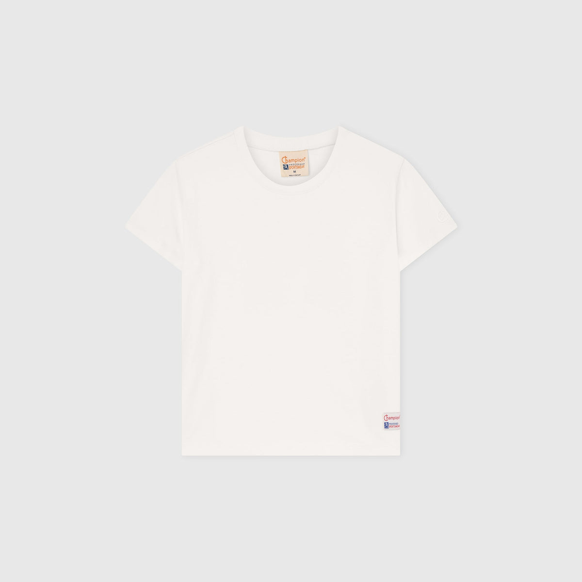 A Women’s Knitted Crewneck T-Shirt by Champion is laid flat on a light gray background, showcasing a relaxed fit with a small Champion logo tag near the bottom hem and a brown label at the neckline. Inspired by Champion’s Reverse Weave heritage, this classic white tee offers everyday comfort and timeless style.