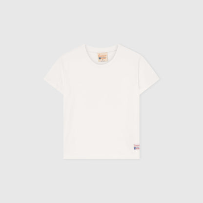 A Women’s Knitted Crewneck T-Shirt by Champion is laid flat on a light gray background, showcasing a relaxed fit with a small Champion logo tag near the bottom hem and a brown label at the neckline. Inspired by Champion’s Reverse Weave heritage, this classic white tee offers everyday comfort and timeless style.