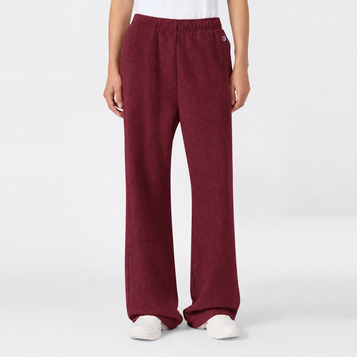 Maroon high-waisted Women’s Knitted Flare Pants by Champion with an elastic waistband and white sneakers.