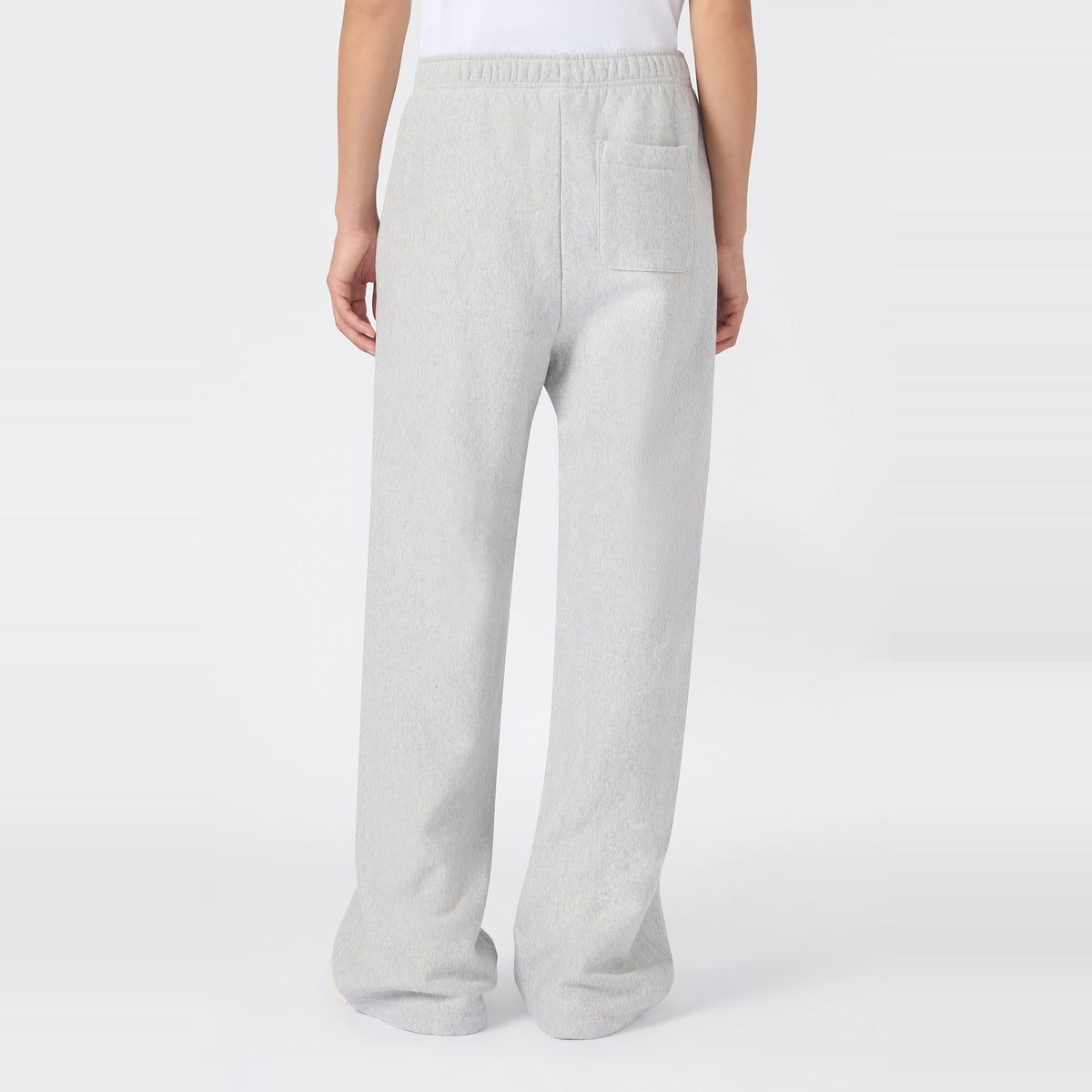 A person wearing Champion Women’s Knitted Flare Pants in light gray, featuring a heavyweight fleece construction, elastic waistband, and a single back pocket—an effortless update on classic women’s flared sportswear, shown from the back against a plain white background.