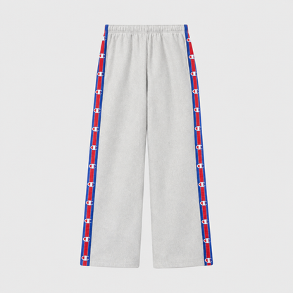Light gray Champion Women’s Knitted Wide Leg Pants featuring a vertical stripe down each leg with a repeating logo pattern in red, white, and blue.