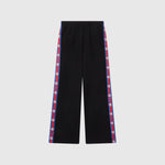 Women’s Knitted Wide Leg Pants by Champion in black, featuring blue and red striped side panels with repeated Champion logos. These pants have a relaxed fit, an elastic waistband, and are photographed against a plain light gray background.