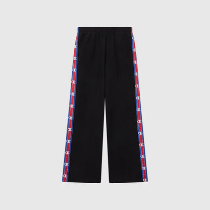 Women’s Knitted Wide Leg Pants by Champion in black, featuring blue and red striped side panels with repeated Champion logos. These pants have a relaxed fit, an elastic waistband, and are photographed against a plain light gray background.