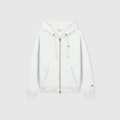 The Champion Women’s Knitted Hooded Full Zip Sweatshirt is a white fleece hoodie featuring a full-length zipper, hood with drawstrings, and front pockets. It is accented with a small blue Champion logo on the left chest and sleeve and is displayed against a plain light background.