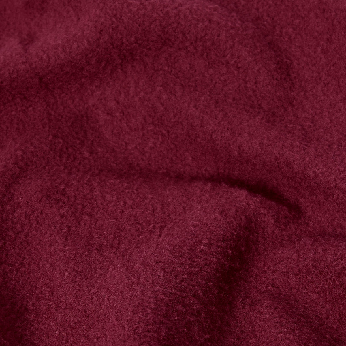 A close-up of the Champion Women’s Knitted Hooded Full Zip Sweatshirt reveals its soft, burgundy-colored knit fabric with a slightly fuzzy texture and gentle folds, evoking the plush comfort of a cozy fleece hoodie.