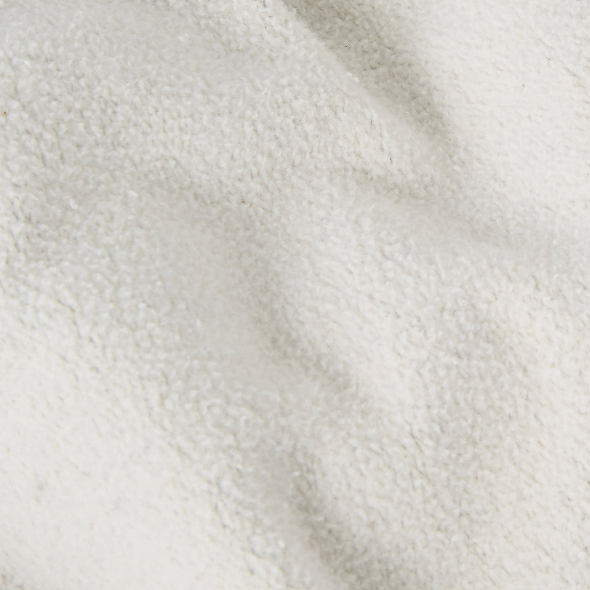 Close-up of a textured, off-white fleece fabric from the Champion Men’s Knitted Hooded Sweatshirt (College Graphic), featuring soft folds and a subtly bumpy surface that evokes the cozy sophistication of college-inspired style.