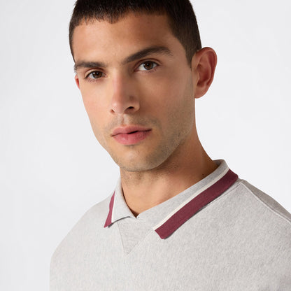A young man with short dark hair wears the Champion Men’s Knitted Polo Neck Sweatshirt in light gray with a burgundy trim, looking toward the camera against a plain white background.
