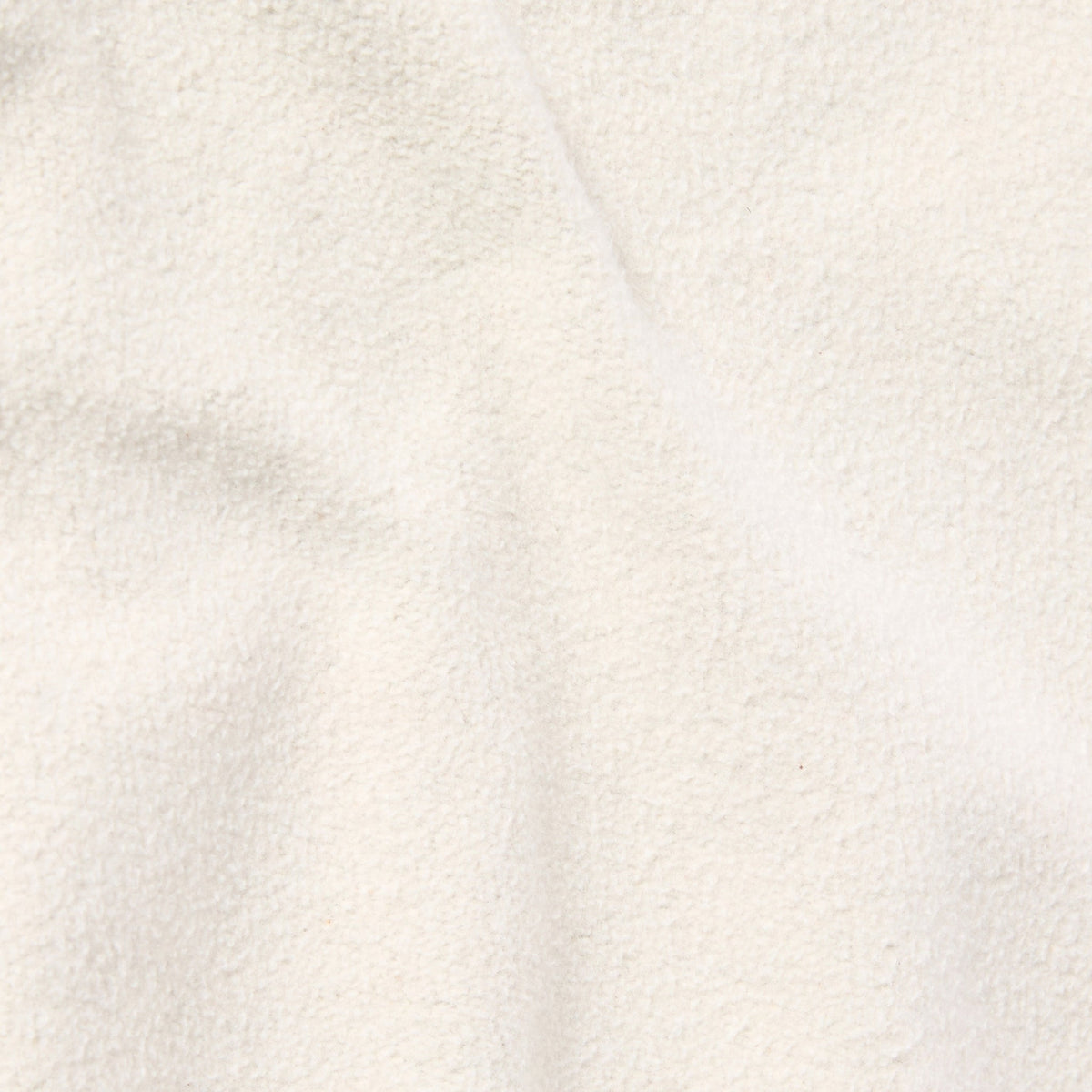Close-up of the soft, cream-colored heavyweight fleece fabric of Champion’s Men’s Knitted Elastic Cuff Pants, with gentle folds creating subtle shadows and highlights—evoking the signature Reverse Weave texture found in classic Champion garments.
