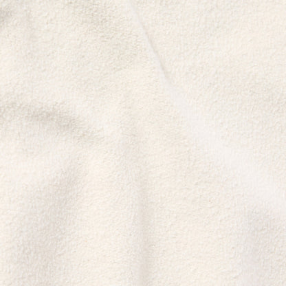 Close-up of the soft, cream-colored heavyweight fleece fabric of Champion’s Men’s Knitted Elastic Cuff Pants, with gentle folds creating subtle shadows and highlights—evoking the signature Reverse Weave texture found in classic Champion garments.