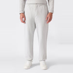 A person is shown from the waist down wearing Champion Men’s Knitted Elastic Cuff Pants in light gray, paired with white sneakers, standing against a plain white background.