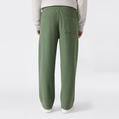 A person is shown from the waist down and viewed from behind, wearing loose-fitting green Men’s Knitted Wide Leg Pants by Champion, featuring a single back pocket and standing against a plain white background.