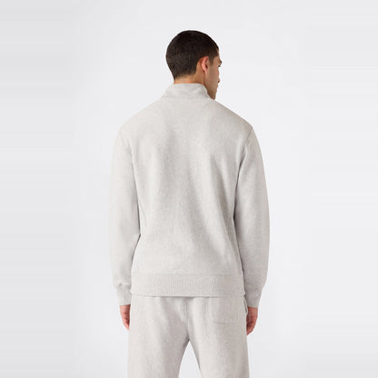 A person wearing a light gray Champion Men’s Knitted Half Zip Sweatshirt and matching sweatpants stands facing away, displaying the back of the outfit against a plain white background and highlighting this classic fleece sportswear look.