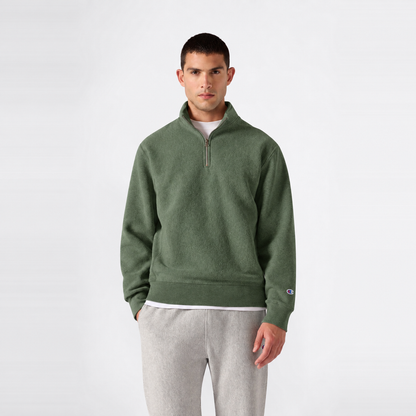 A person wears a green Men’s Knitted Half Zip Sweatshirt by Champion over a white t-shirt and light gray sweatpants, standing against a plain white background.