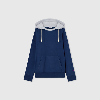 Men’s Knitted Hooded Sweatshirt (Vintage Wash) by Champion in blue, featuring a front pocket, long sleeves, and a light gray hood lining with drawstrings. Crafted from soft Reverse Weave fleece, this hoodie showcases the classic Champion logo on the left sleeve. The sweatshirt is laid flat on a plain light background, highlighting its timeless style and comfort.
