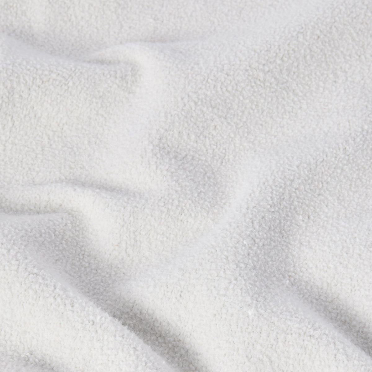 A close-up of a soft, white, textured fabric with gentle folds and shadows evokes a cozy, plush feel—similar to the signature Reverse Weave technique found in the Champion Men’s Knitted Crewneck Sweatshirt (Reversible + Vintage Wash).