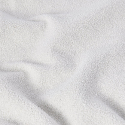 A close-up of a soft, white, textured fabric with gentle folds and shadows evokes a cozy, plush feel—similar to the signature Reverse Weave technique found in the Champion Men’s Knitted Crewneck Sweatshirt (Reversible + Vintage Wash).