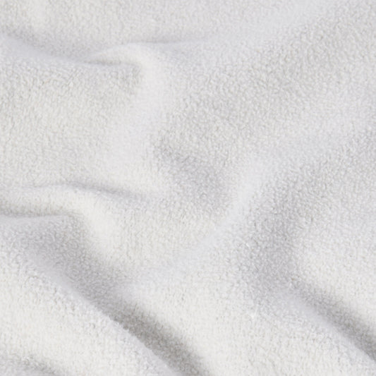 A close-up of a soft, white, textured fabric with gentle folds and shadows evokes a cozy, plush feel—similar to the signature Reverse Weave technique found in the Champion Men’s Knitted Crewneck Sweatshirt (Reversible + Vintage Wash).