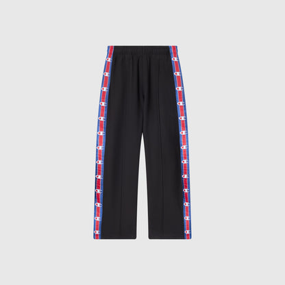 Champion Men’s Knitted Straight Hem Pants with an elastic waistband and vertical red and blue side stripes featuring repeating white logos along the outer seams, showcased against a plain light gray background—these fleece trousers blend sportswear inspiration and comfort, capturing the classic style of Champion’s heritage.