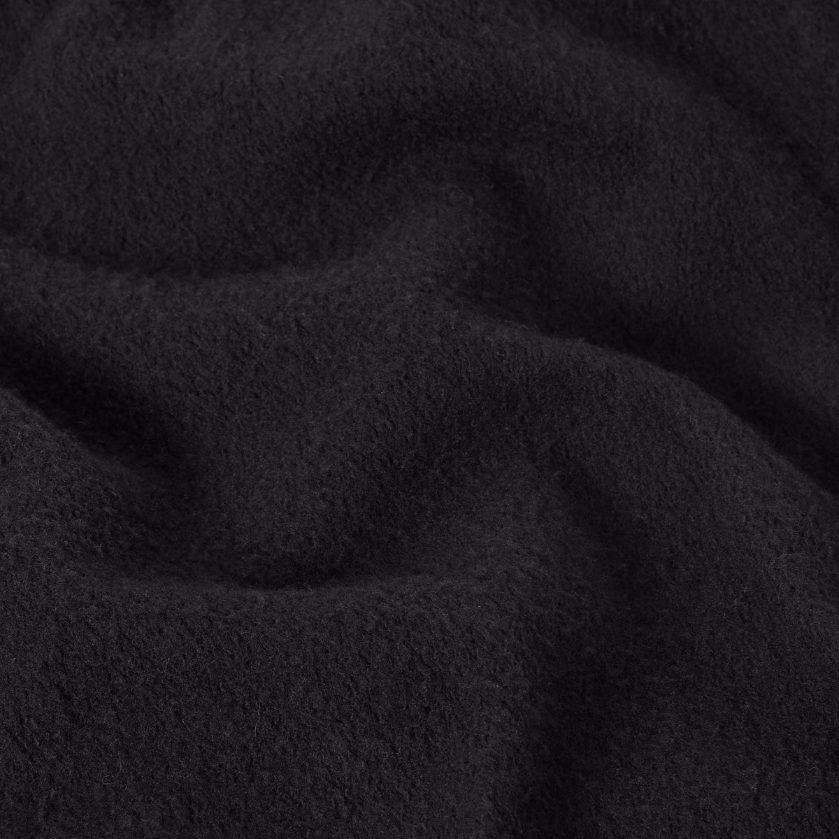 Close-up of black fleece fabric showing a soft, textured surface with gentle folds and shadows, evoking the comfort featured in Champion Men’s Knitted Straight Hem Pants.