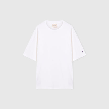 A Men’s Knitted T-Shape Tee by Champion is laid flat on a light gray background. Crafted from heavyweight cotton, this sportswear essential features a small embroidered Champion logo on the left sleeve and a visible neck tag inside the collar.