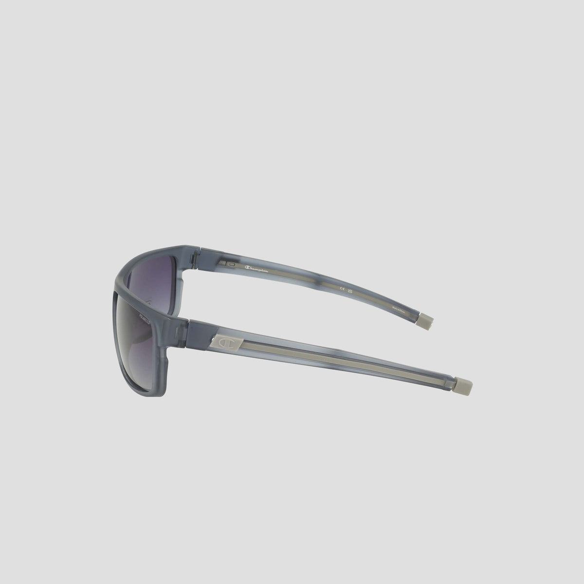 Champion Men's Polarized Wrap - Large sunglasses in gray, featuring rectangular bio-based frames with dark polarized lenses, viewed from the side and showcasing metallic accents near the hinges, set against a plain light background.