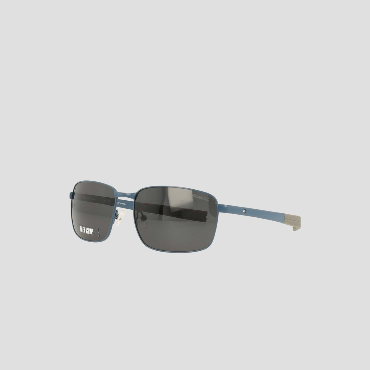 Champion Men's Polarized Stainless ST-Shirtl Flex Grip Tip sunglasses feature rectangular dark lenses set in thin blue metal frames, highlighted by silver flex grip temple tips. Designed for active lifestyles with polarized lenses, these sunglasses are showcased against a plain light gray background.
