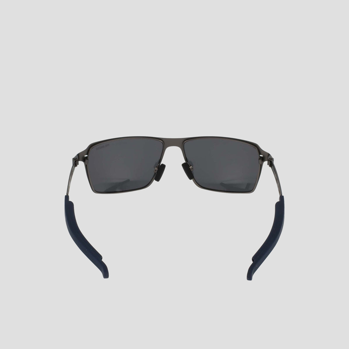 The Champion Men's Polarized Stainless ST-Shirtl Comfort Fit sunglasses feature rectangular black frames, dark polarized lenses, and navy blue curved earpieces with adjustable rubber tips, shown against a light gray background.