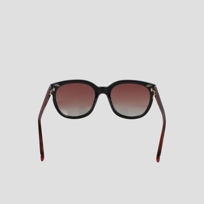 Introducing the Champion Women's Polarized Curvaceous Square sunglasses, crafted from luxury acetate eyewear. These sunglasses feature dark gradient lenses set in bold black frames, with distinctive outward-curving reddish-brown arms. Presented against a plain light gray background, this pair offers both elegance and protection.