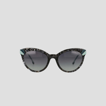 Champion’s Women's Polarized Cateye sunglasses feature black and gray marbled frames, dark gradient lenses, and distinctive teal accents at the upper outer corners. Displayed against a simple light background, these chic cat-eye sunglasses not only offer practical sun protection with their polarized gradient lenses but also elevate your style.