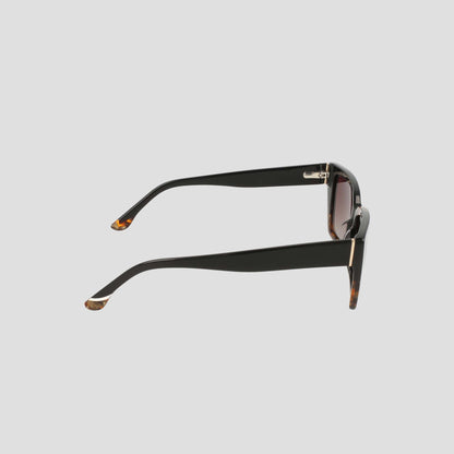 Side view of Champion Women's Polarized Slim Rectangle sunglasses in black, showcasing handmade acetate frames with thick arms, brown tortoiseshell accents, and laminated color block tips, set against a light gray background.