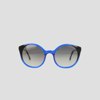 Champion's Women's Polarized Flirty Round sunglasses, featuring blue rims, black temples, and gradient lenses in handmade acetate for a refined finish, are displayed against a plain light gray background.